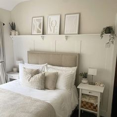 a bed with white sheets and pillows in a bedroom next to a window that has pictures on the wall above it