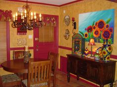 a dining room with sunflowers on the wall and red painted door, chandelier