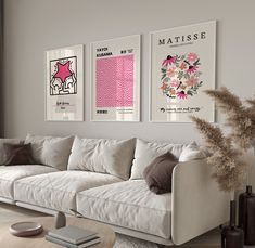 a living room with white couches and pink art on the wall above them in front of a window