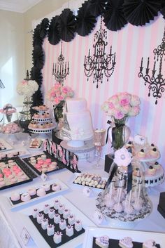 a table topped with lots of cakes and cupcakes next to a chandelier