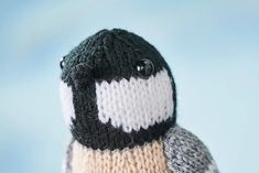 a close up of a stuffed penguin wearing a knitted hat with buttons on it