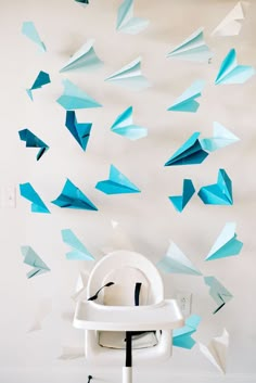 blue origami birds are flying in the air above a white highchair