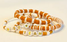 Show off your team or school pride with this customizable burnt orange and white bracelet set This stack comes with 4 bracelets and uses the following material: -orange and white heishi beads -orange and white seed beads -letter and heart beads -Powercord or Stretch Magic brand elastic Personalize these with any word or phrase you would like (ex: HOOK EM HORNS, etc) We are able to add a 3rd accent color, if you would like that please leave that information in the personalization section.  If you do not have a tape measure, you can use a string and ruler to measure your wrist. Wrap the string around your wrist then use a ruler to measure the length of the string. Our bracelets come in standard sizes between 6-7 inches. However, we can modify the size, if needed. DM us if you need assistance School Spirit Jewelry, Hook Em Horns, White Bracelet, Wrist Wrap, School Pride, White Bracelets, Heishi Beads, Heart Beads, School Spirit