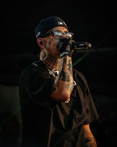 a man with tattoos and piercings holding a microphone