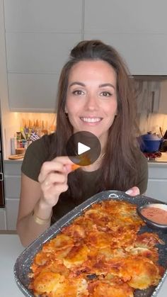 a woman is holding up a pan of food