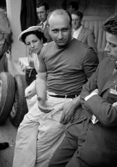 black and white photograph of men sitting on the ground with one man looking at his cell phone