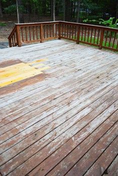 a wooden deck with railings and trees in the background