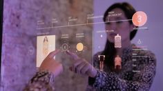 a woman is drawing on a glass board with buttons and other items in the background