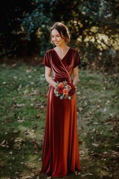 a woman in a long red dress holding a bouquet