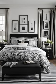 a bedroom with black and white bedding, pictures on the wall, and an ottoman