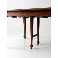 an old wooden table with two legs and a drawer on one end, sitting against a white wall