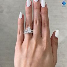 a woman's hand with white manicured nails and an engagement ring