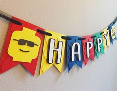 a happy birthday banner hanging on the wall with legos cut out to spell it's name