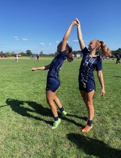 two girls are playing frisbee in a field