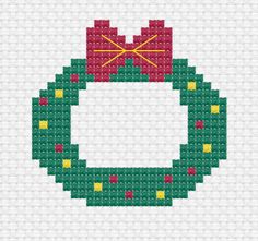 a cross stitch christmas ornament with a red bow on it's side