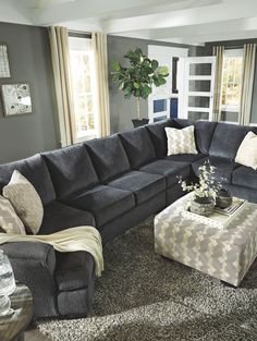 a living room filled with furniture and a large couch in front of a window on top of a rug