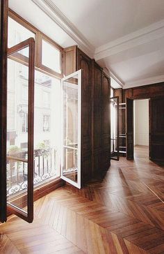 an empty room with wooden floors and large windows on the wall, in front of a balcony