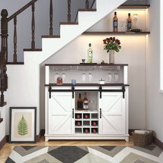 a white cabinet under a stair case with wine glasses and bottles on it in front of a staircase