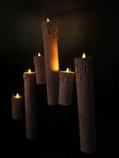 several candles are lit in the dark with white paper wrapped around them and placed on top of each other