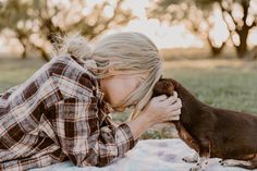 a woman laying on top of a blanket next to a dog