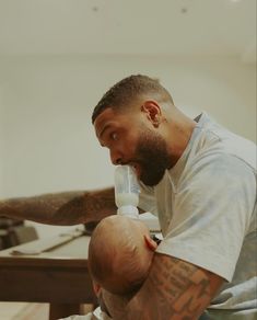 a man holding a baby in his lap while using a bottle to drink from it