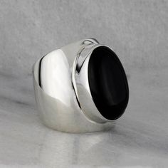 This chunky silver ring is the embodiment of classic charm with a contemporary twist. The centerpiece of this ring is a luxurious oval black onyx gemstone. With its deep, rich black hue, the onyx brings an air of mystery and elegance to the design. The band is designed with a generous width, adding a modern and bold flair to the ring. Winner! Gemstone - Genuine Black Onyx 925 Sterling Silver High polish finish Approx. 1" L Signed by the artist Handcrafted in Taxco, Mexico Wide Silver Ring, Chunky Silver Rings, Wide Band Ring, Black Onyx Stone, Crafts Jewelry, Onyx Gemstone, Wide Band Rings, Diy Crafts Jewelry, Onyx Stone