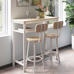 two stools sit at the bar in front of a potted plant and window