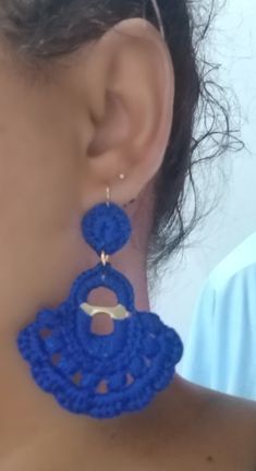 a woman wearing large blue crochet earrings