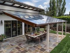 an outdoor dining area with a table and chairs under a large solar panel on the roof