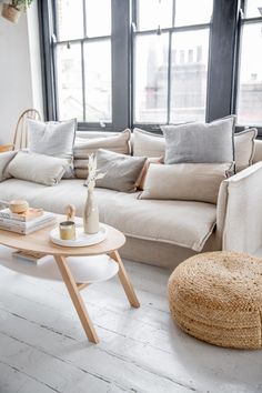 a living room filled with lots of furniture next to large windows and a round coffee table