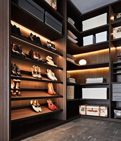 a walk in closet filled with lots of shoes and boxes on top of wooden shelves