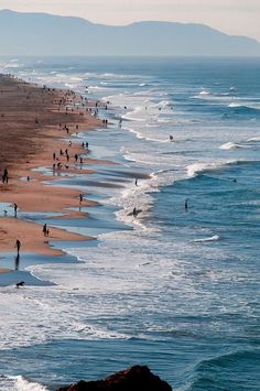 many people are walking on the beach near the water