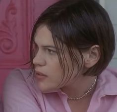 a close up of a person wearing a pink shirt and looking off to the side