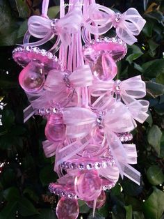 a pink ornament hanging from a tree filled with lots of beads and bows