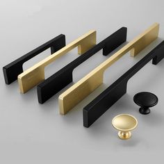 an assortment of black and gold hardware on a gray surface with one door handle in the middle