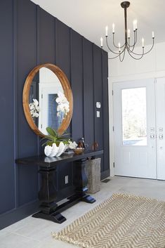 a room with a table, mirror and chandelier on the wall in front of it