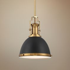 a black and gold pendant light hanging from a ceiling fixture in a room with beige walls