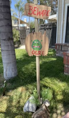 a wooden sign that says beware and ogre on it in front of a house