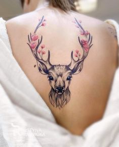 the back of a woman's shoulder with a deer head and flowers on it