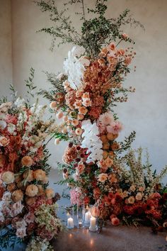 an arrangement of flowers and candles on a table