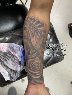 a person with a black and grey tattoo on their arm holding a rose in front of them