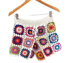 a crocheted shorts hanging on a wooden hanger with clothes pins attached to it