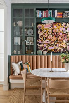 a dining room table with two chairs and a bookcase in the back wall behind it