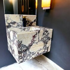 a marble sink in a bathroom next to a wall mounted toilet paper dispenser