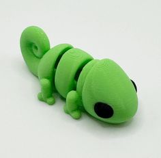 a green gecko toy laying on top of a white surface