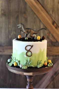 a birthday cake with a dinosaur topper on it's side and the number eight