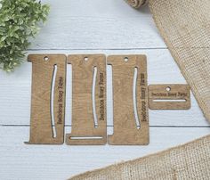 three wooden luggage tags sitting on top of a white table next to a potted plant