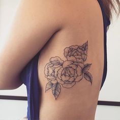 a black and white photo of a woman's shoulder with a rose tattoo on it