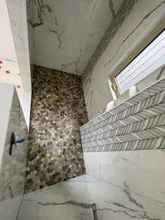 a bathroom with white and grey tiles on the walls, flooring and shower stall