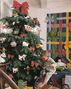 a young boy riding a bike next to a christmas tree with presents on the floor